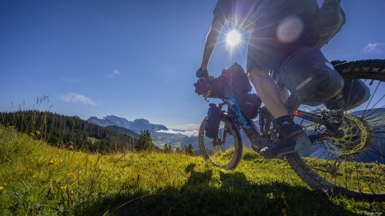 Mountainbiketour mit FullyLoaded Pro Gepäckträger. Fotografiert gegen die Sonne bei blauem Himmel.